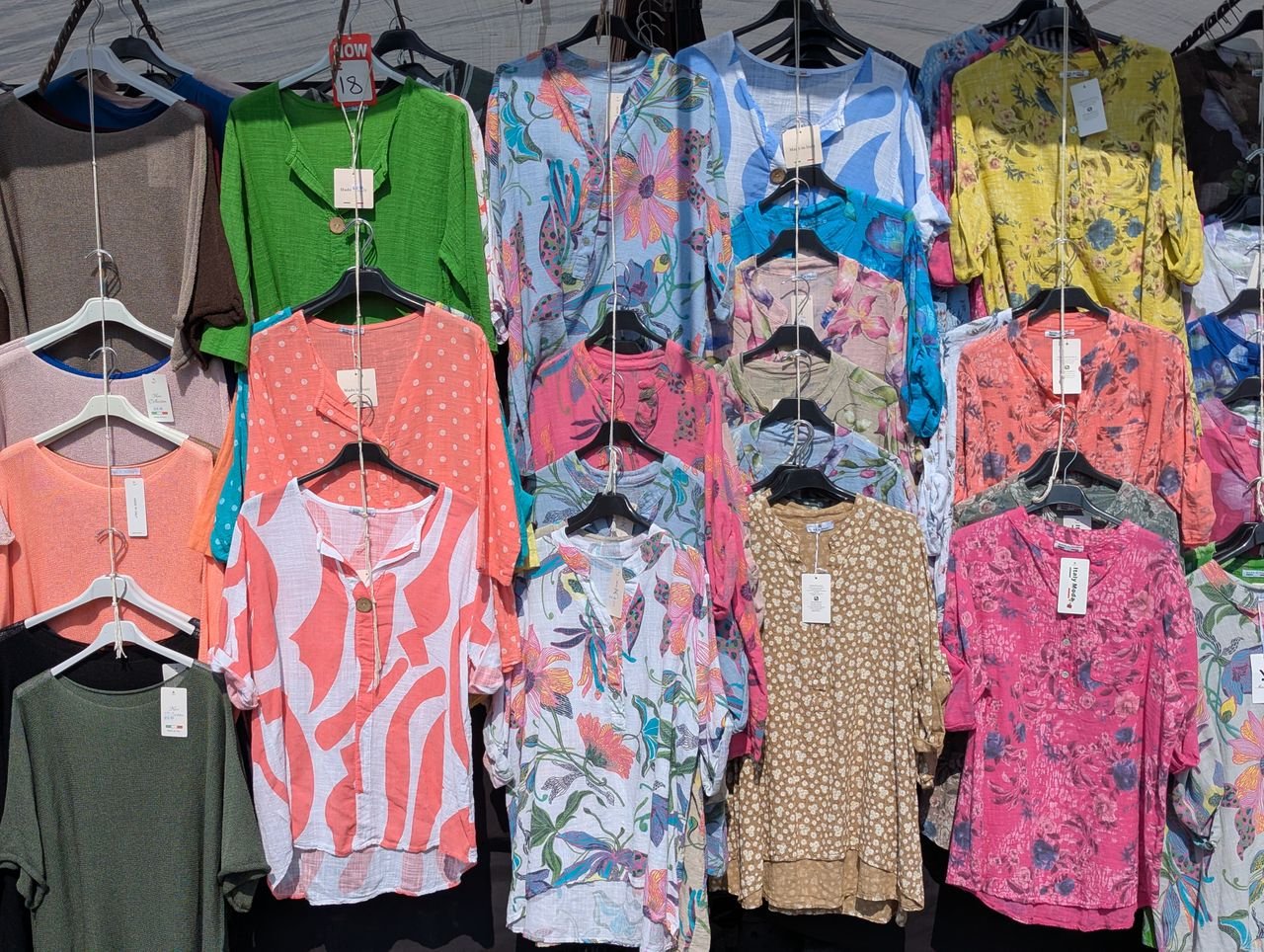A vibrant display of summer blouses in various patterns, showcased at a market in Knaresborough, England.