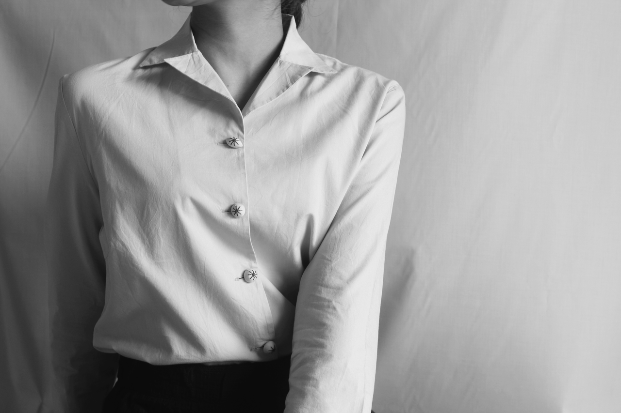 Black and white close-up portrait of a woman in a button-up shirt.